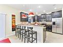 Modern kitchen with dark cabinetry, stainless steel appliances, and an island with seating at 1423 Thunderbird Rd, Davenport, FL 33896