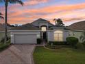 One-story home with a two-car garage and landscaped yard at sunset at 235 Royal Palm Dr, Davenport, FL 33837