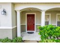 Inviting house entrance with red door, columns, and landscaping at 12913 Oulton Cir, Orlando, FL 32832