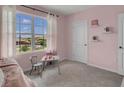 Pink bedroom with a small table and chairs, and a large window at 2626 Sage Valley Way, Winter Haven, FL 33884