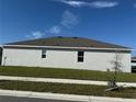 Rear view of a one-story home with a gray exterior and mature landscaping at 5231 Maddie Dr, Haines City, FL 33844