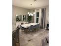 Modern dining room with white table, gray chairs, and a statement light fixture at 14739 Glade Hill Park Way, Winter Garden, FL 34787