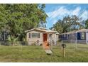 Tan house with red door, landscaping, and fenced yard at 1506 W 12Th St, Sanford, FL 32771