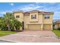 Two-story house with a three-car garage, paver driveway, and lush landscaping at 2760 Rialto Ct, Kissimmee, FL 34746