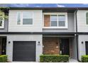 Modern two-story townhome with gray and wood siding, two-car garage, and landscaped lawn at 4410 Le Reve Ct, Kissimmee, FL 34746