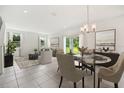 Dining area with round glass table, beige chairs, and access to the backyard at 9150 Harris Hawk Dr, Leesburg, FL 34788