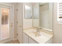 Small bathroom with single sink, mirror, and door to outside at 1907 Lazy Oaks Loop, Saint Cloud, FL 34771