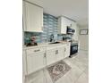 Modern kitchen with white cabinets, stainless steel appliances, and blue tile backsplash at 301 E 26Th St, Sanford, FL 32773