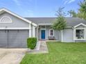 Gray house with a blue door and a landscaped front yard at 7471 Crooked Lake Cir, Orlando, FL 32818