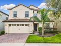 Two-story house with beige exterior, a three-car garage, and a landscaped front yard at 1522 Moon Valley Dr, Davenport, FL 33896