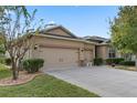 Two-story house with beige siding, three car garage, and neatly landscaped yard at 5307 Cortland Dr, Davenport, FL 33837