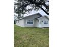 Side view of a charming light gray house with green lawn at 603 Maggie Cir, Winter Haven, FL 33880
