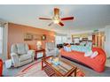 Living room with orange couches, ceiling fan, and coffee table at 2466 Sweetwater Club Cir # 1, Kissimmee, FL 34746