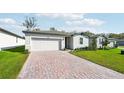 One-story home with white siding, white garage door, and a brick paver driveway at 28054 Poppy Ct, Leesburg, FL 34748