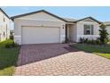 Two-car garage with a brick paver driveway and landscaped lawn at 4706 Jasmine Cir, Leesburg, FL 34748