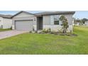 Gray house with light blue shutters, landscaping, and a brick driveway at 4751 Jasmine Cir, Leesburg, FL 34748