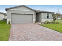 House exterior with gray siding, stone accents, and a brick paver driveway at 4751 Jasmine Cir, Leesburg, FL 34748