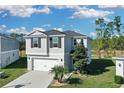 Two-story house with gray siding, two-car garage, and landscaped yard at 216 Miles Ct, Davenport, FL 33837