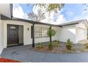 Front entrance with a black door, white brick facade, and landscaping at 103 Bonita Pl, Ormond Beach, FL 32174