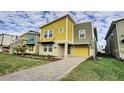 Two-story modern home with yellow and gray exterior, paved driveway, and landscaped lawn at 2736 Bookmark Dr, Kissimmee, FL 34746