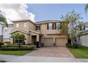 Two-story house with tan siding, three-car garage, and landscaped yard at 9036 Arbors Edge Trl, Windermere, FL 34786
