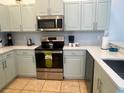 Bright and modern kitchen showcasing stainless steel appliances and light green cabinets at 148 Brunello Dr, Davenport, FL 33897