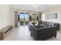 Living room with gray sofas, coffee table, and sliding glass doors leading to a patio with water views at 470 Lake Shore Pkwy, Davenport, FL 33896