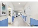 Bright hallway with light tile floors and blue accent walls, offering views into living and bathroom areas at 1540 Maidstone Ct, Davenport, FL 33896