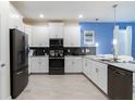 Modern kitchen with white cabinets, dark appliances, and a large island at 1540 Maidstone Ct, Davenport, FL 33896