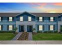 Evening view of two-story townhomes with light blue and gray siding and landscaped yards at 617 Jasmine Ln, Davenport, FL 33897