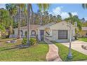 Exterior view of a house with a landscaped lawn and palm trees at 2460 Oak Mill Dr, Kissimmee, FL 34744
