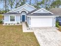 Gray house with white garage door and blue front door, landscaping, and driveway at 308 Halstead Dr, Davenport, FL 33897