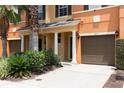 Townhouse exterior with attached garage, landscaping, and palm trees at 875 Assembly Ct, Reunion, FL 34747