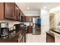 Modern kitchen with dark wood cabinets, granite countertops, and stainless steel appliances at 875 Assembly Ct, Reunion, FL 34747