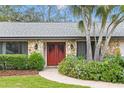 Front entrance with red double doors, stone accents, and flowering bushes at 369 Forest Park Cir, Longwood, FL 32779