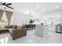 Open concept kitchen and living area with white cabinets, marble floors, and a brown sectional sofa at 397 Madison Dr, Davenport, FL 33837