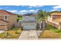 Two-story house with gray siding, a two-car garage, and a landscaped yard, near a lake at 3902 Rollingsford Cir, Lakeland, FL 33810