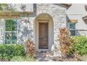Elegant front entrance with arched stonework and a wood door at 8441 Chilton Dr, Orlando, FL 32836