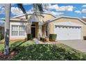 House exterior featuring a two-car garage and attractive landscaping at 8160 Fan Palm Way, Kissimmee, FL 34747