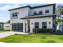 Modern two-story house with a white exterior, gray driveway, and lush landscaping at 1606 Hart Ln, Orlando, FL 32804