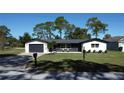 Newly renovated home with modern facade, dark gray garage door, and manicured lawn at 12617 Pine Island Dr, Leesburg, FL 34788