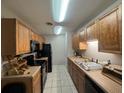 A galley-style kitchen with wood cabinets and black appliances at 1695 Lee Rd # B216, Winter Park, FL 32789