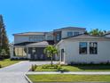 Luxury two-story home with gray roof, palm tree, and paved driveway at 7233 Wild Blackberry Trl, Winter Garden, FL 34787