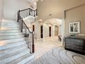 Large marble staircase with a metal railing and views to the living and dining areas at 6245 Little Lake Sawyer Dr, Windermere, FL 34786