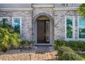 Elegant entryway with arched door, stone facade, and landscaping at 8192 Ludington Cir, Orlando, FL 32836