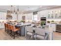 Modern white kitchen with gray island, stainless steel appliances, and seating for six at 932 Tassleflower Trl, Saint Cloud, FL 34771