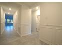 View down a bright hallway with wainscoting and tile flooring at 3961 Ambrose Ave, Kissimmee, FL 34746