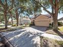 Two story house on a tree lined street with a tan exterior and a two car garage at 8320 Via Bella Notte, Orlando, FL 32836