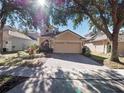 Tan two-story house with a two-car garage and lush landscaping at 8320 Via Bella Notte, Orlando, FL 32836