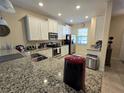 Modern kitchen with white cabinets, granite counters, and stainless steel appliances at 9037 Shadow Mountain St, Davenport, FL 33896